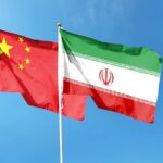Flags of China and Iran waving against a blue sky