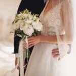 Bride holding a bouquet with groom's hand on her waist