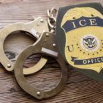 Handcuffs and a police badge on a wooden surface