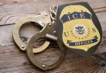 Handcuffs and a police badge on a wooden surface