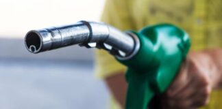 Close-up of a hand holding a green fuel pump nozzle