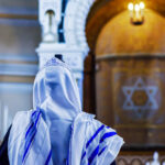 A person wearing a tallit in a synagogue during prayer