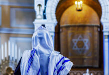 A person wearing a tallit in a synagogue during prayer