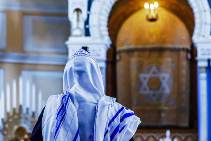 A person wearing a tallit in a synagogue during prayer