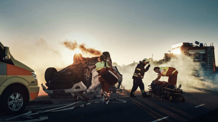 Emergency responders at an overturned, smoking car on a roadway