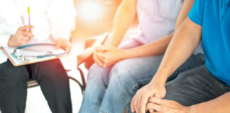 Patients sitting with a doctor holding a clipboard