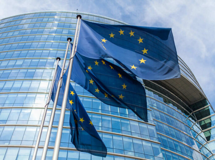 European Union flags waving outside glass building