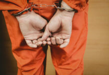 Person in orange jumpsuit handcuffed from behind