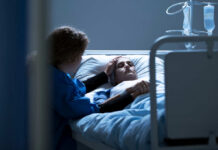 Patient in hospital bed comforted by visitor