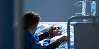 Patient in hospital bed comforted by visitor