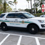 Inflated Arrests? Florida’s Numbers Don’t Add Up Sheriff SUV parked in a lot near palm trees