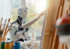 Robot painting on a canvas in art studio.