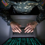 Cheap Phone Data Targets U.S. Bases A soldier in U.S. Army uniform typing on a laptop with green code displayed on the screen