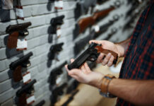 Supreme Drama: Maryland’s Gun Law Twist Angers Advocates Person holding a handgun in a gun shop with various firearms displayed on the wall