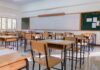 An empty classroom with wooden desks and a chalkboard