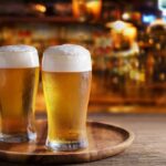 Glyphosate Found in Popular Beer Brands Two glasses of beer on a wooden tray in a bar setting