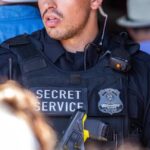 A Secret Service officer in tactical gear with a radio and firearm