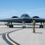 B-21 Raider Tests Surge Ahead At Edwards A military personnel stands in front of a B-2 Spirit stealth bomber on an airfield