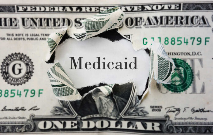 A torn dollar bill revealing the word 'Medicaid'
