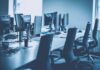 An empty office workspace with multiple computer monitors and chairs
