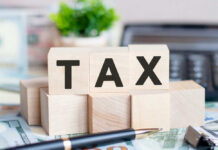 Wooden blocks spelling tax on desk background