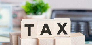 Wooden blocks spelling tax on desk background