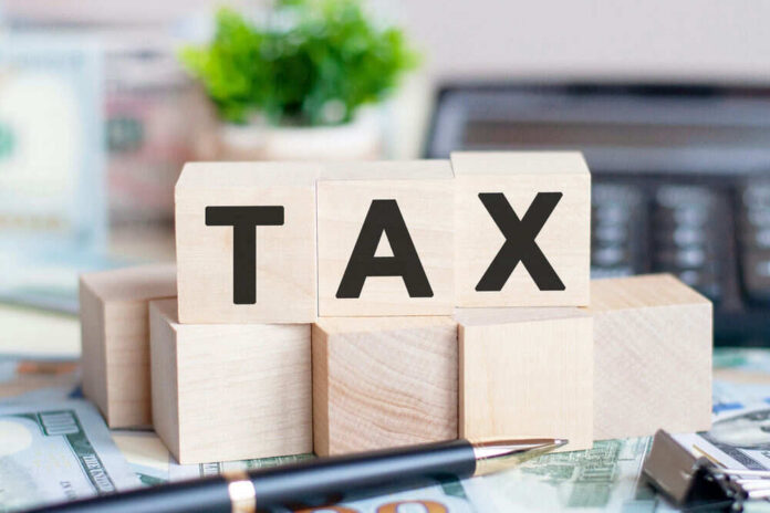 Wooden blocks spelling tax on desk background