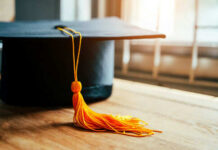 Graduation cap with yellow tassel on table