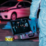 Staten Island Cab Lure Horror Forensic investigator at crime scene with police car.