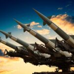$35B Missiles — Funding Trap Ahead Cruise missile launcher with missiles pointed upwards against a sunset sky