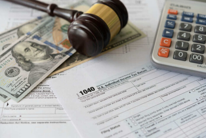 Tax forms with a gavel, cash, and a calculator