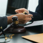 Fashion Powerhouse Implicated In Teen Trafficking Hands of professionals discussing documents beside a judge's gavel