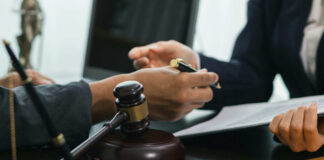 Hands of professionals discussing documents beside a judge's gavel