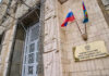 Russian ministry building entrance with ornate metal door and flags