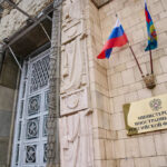 Russian ministry building entrance with ornate metal door and flags