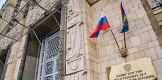 Russian ministry building entrance with ornate metal door and flags