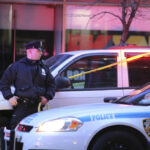 Harlem Subway Horror — Predator Still Loose Police officer standing near a crime scene with vehicles and caution tape