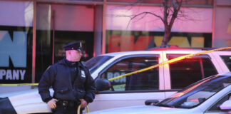 Police officer standing near a crime scene with vehicles and caution tape