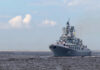 Large gray naval warship sailing on open water