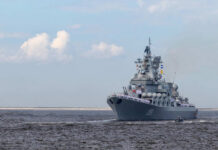 Large gray naval warship sailing on open water