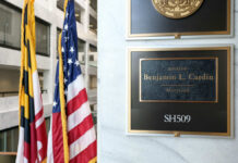 War Department Guts Religion List Overnight Office plaque beside U.S. and state flags in a government building