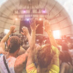 Crowd at a music festival with hands raised in celebration