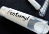 A glass container labeled 'Fentanyl' with a white powder inside