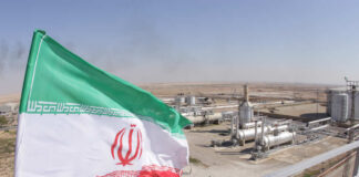 Iranian flag waving in front of an oil processing facility