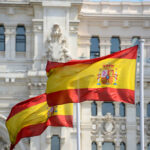 Holy Wildcard: Pope Picks Cells Over Palaces Two Spanish flags waving in front of a historic building