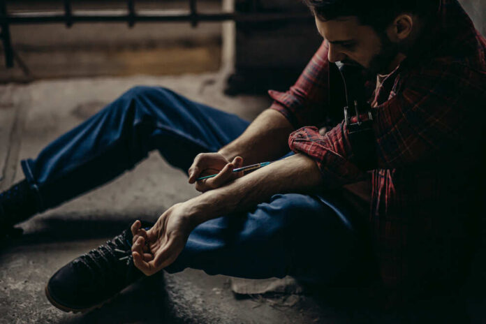 Drug,User,Suffer,From,Narcotic,Addiction,,He,Is,Obsessed,With man sitting on floor injecting his arm with a syringe