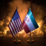 Trump Trades Blocks For Barrels—At What Price? Flags of the United States and Iran displayed on stands with a smoky background