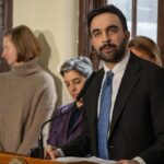 Insiders Rocked: Left Flamethrower Wins Man in suit speaking at a podium with people standing behind