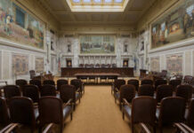 Scotland’s Two-Tier Justice Exposed Interior view of a courtroom with wooden benches and large murals