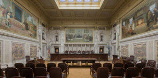Interior view of a courtroom with wooden benches and large murals